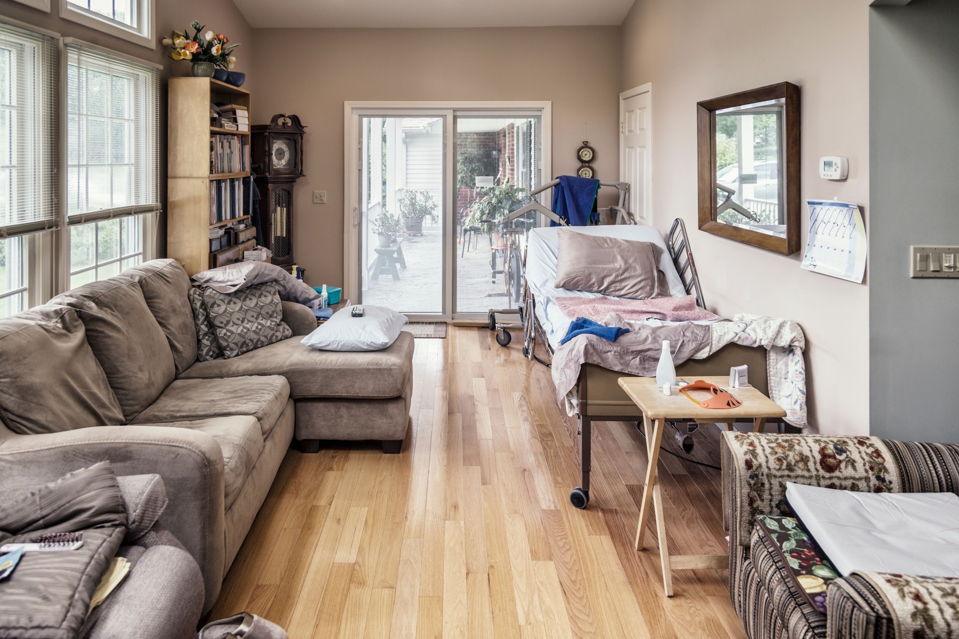Raised Hospital Bed In Cluttered Private Residence Living Room